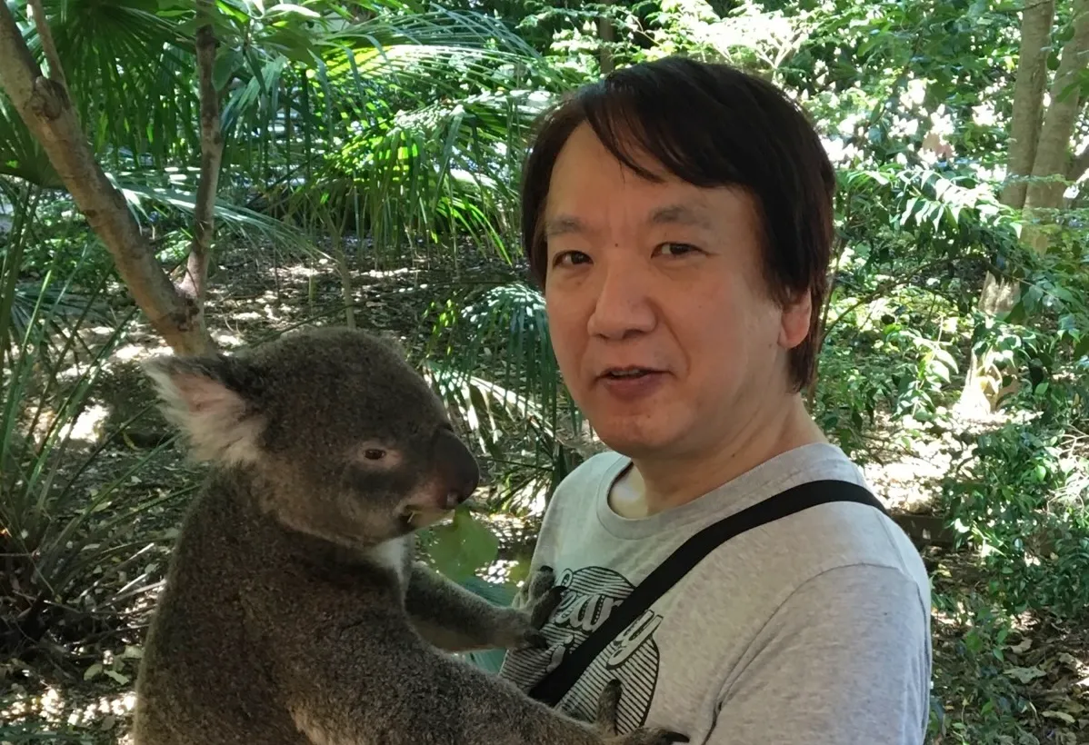 Koji Annoura holding a koala in a forest