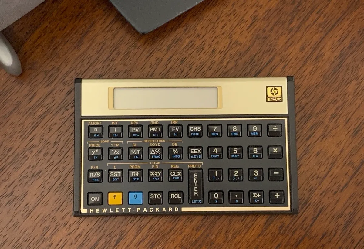 A vintage Hewlett-Packard calculator on a wooden desk